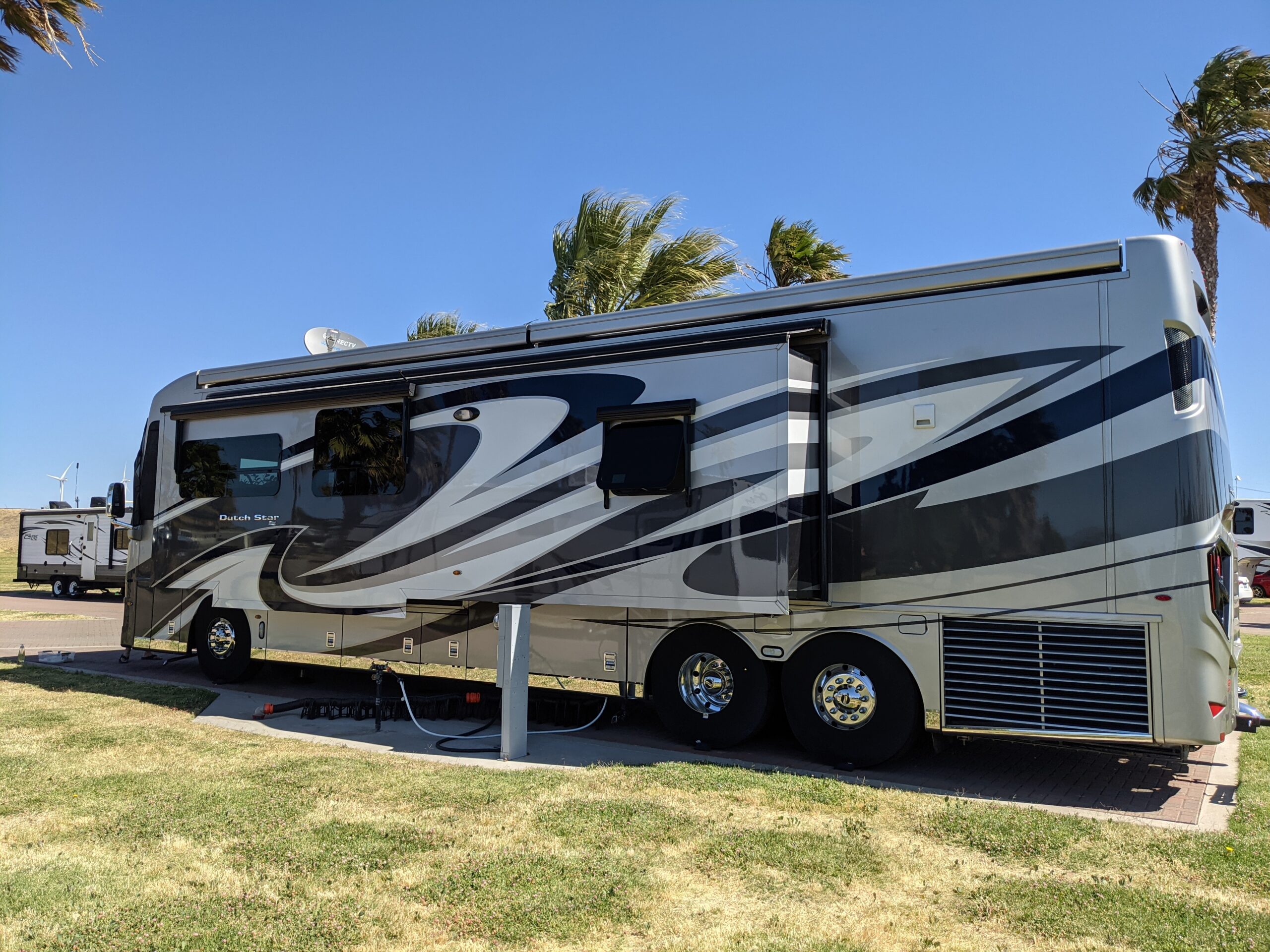 A motorhome with its awning out on a grassy site beside palm trees at Rio Viento