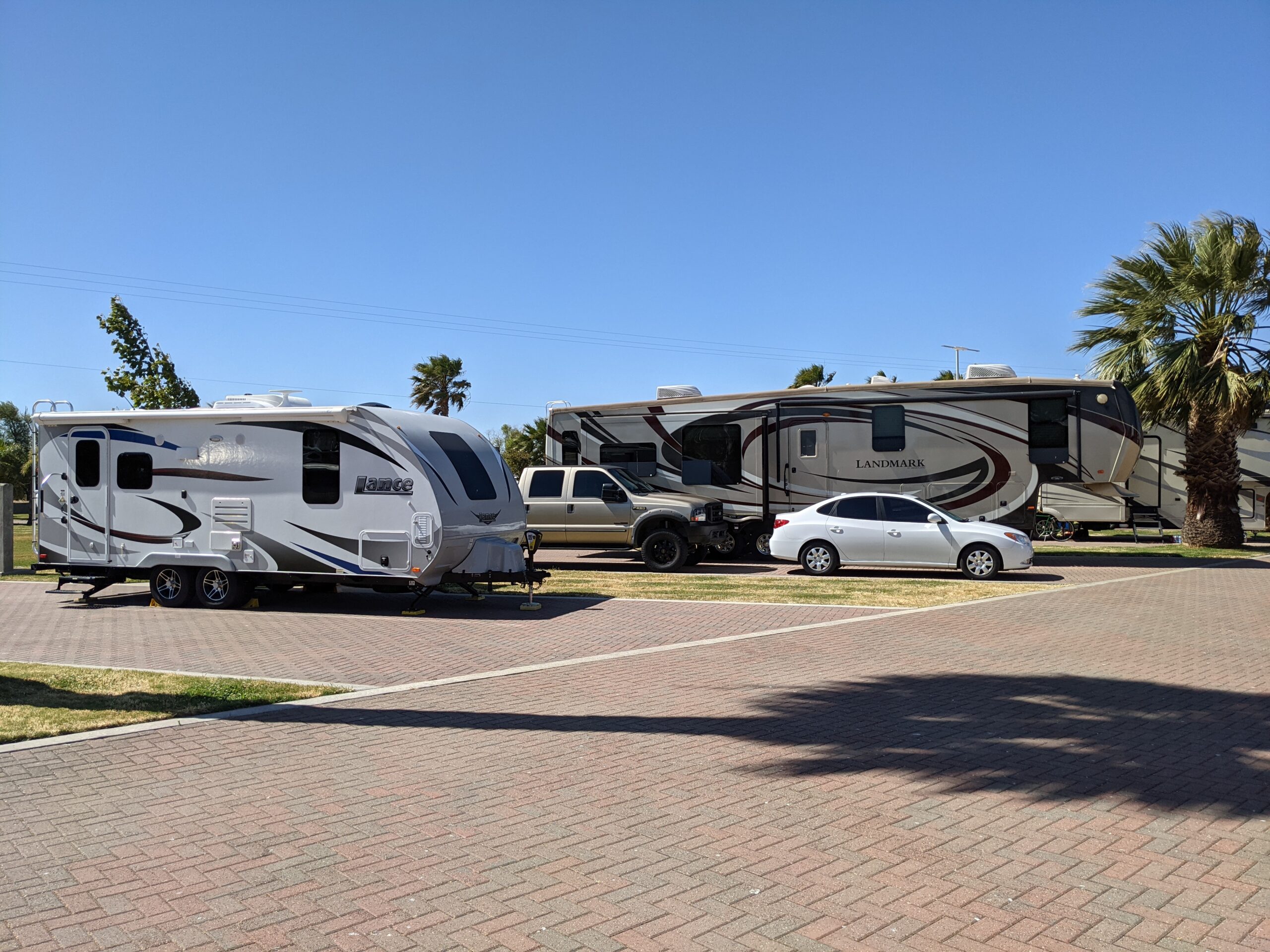 Travel trailers parked on paved sites bordered by lawn at Rio Viento RV Park