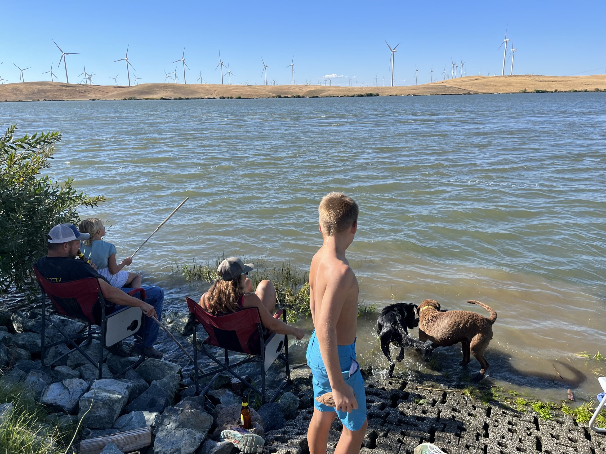 A family fishing from the riverbank at Rio Viento on a summer afternoon
