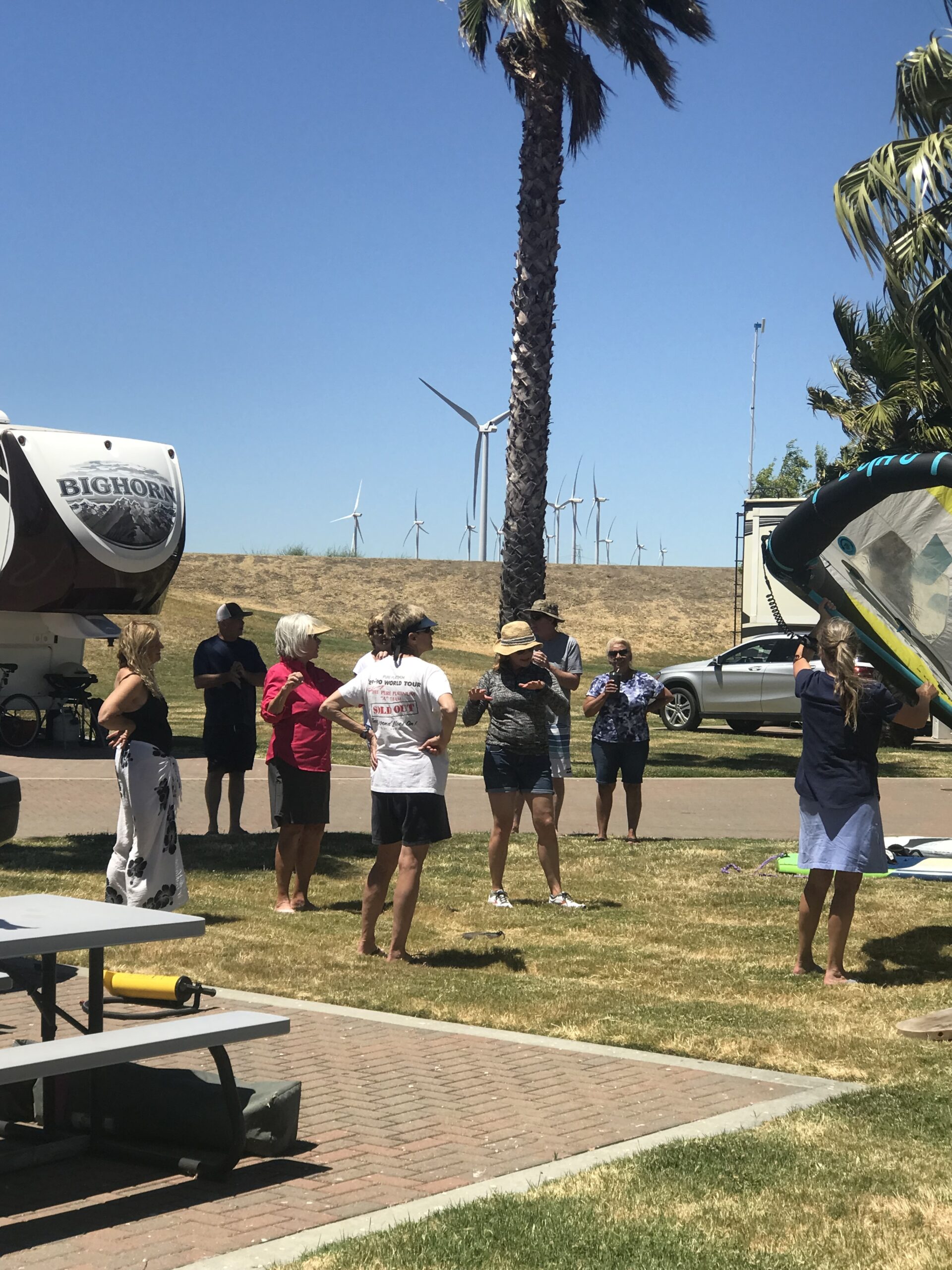 Guests gathered on the lawn at Rio Viento with wing foiling gear, wind turbines on the ridge behind
